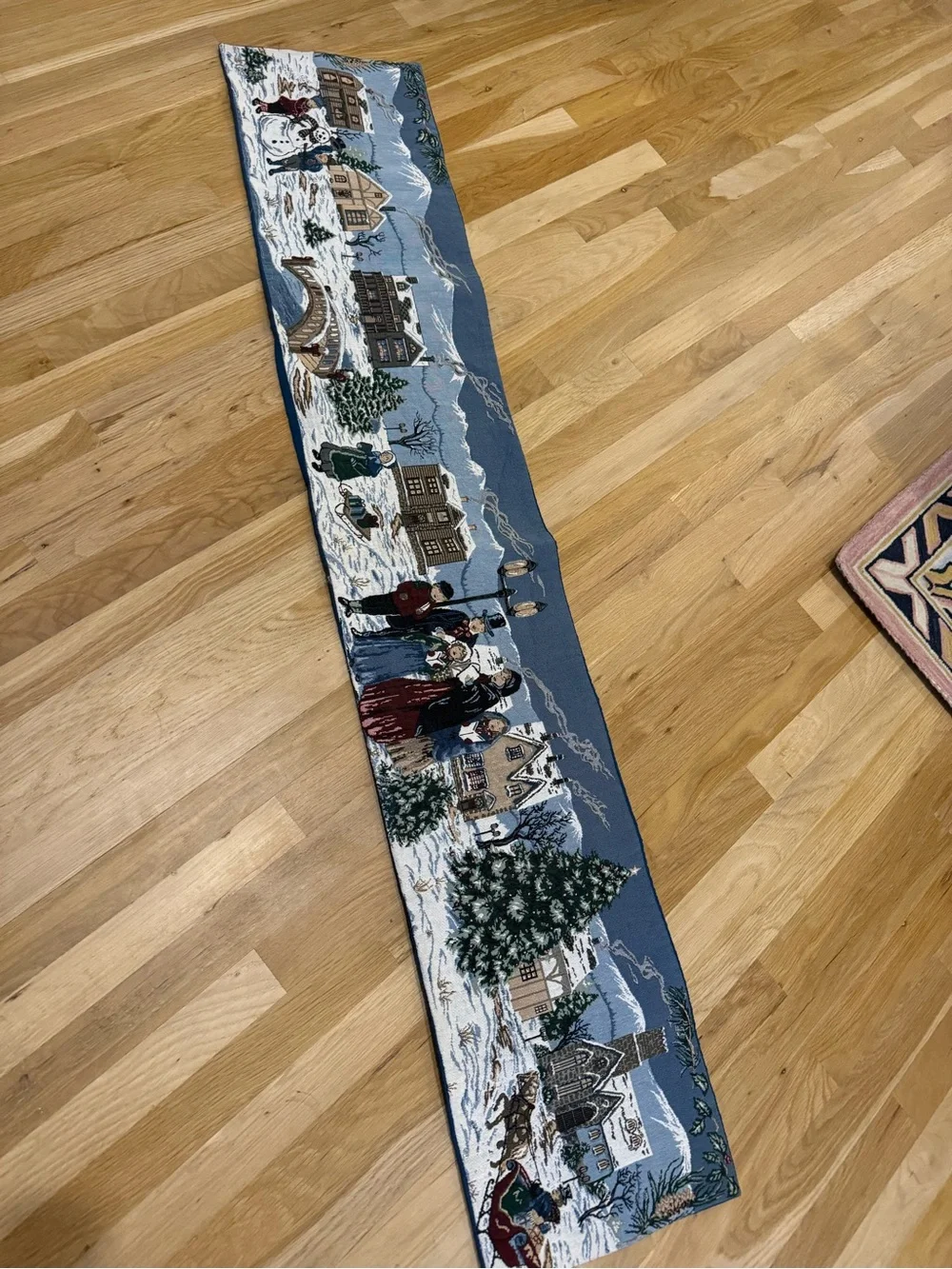 holiday-themed tapestry table runner featuring a snowy village 64”